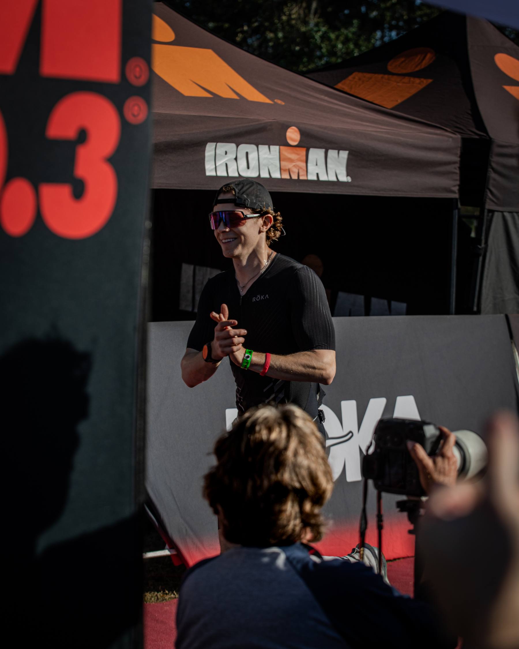Aidan smiling and clapping in front of the IRONMAN tent at IRONMAN 70.3 Florida