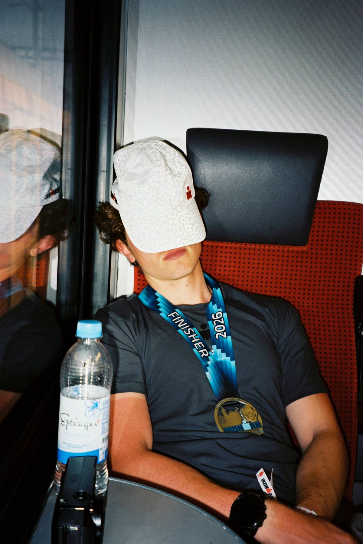 Aidan asleep on a train after the race, cap over his eyes and a finisher medal around his neck
