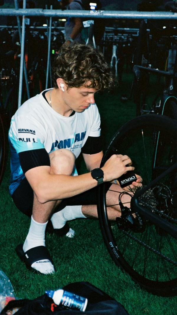 Aidan kneeling to check his bike in transition