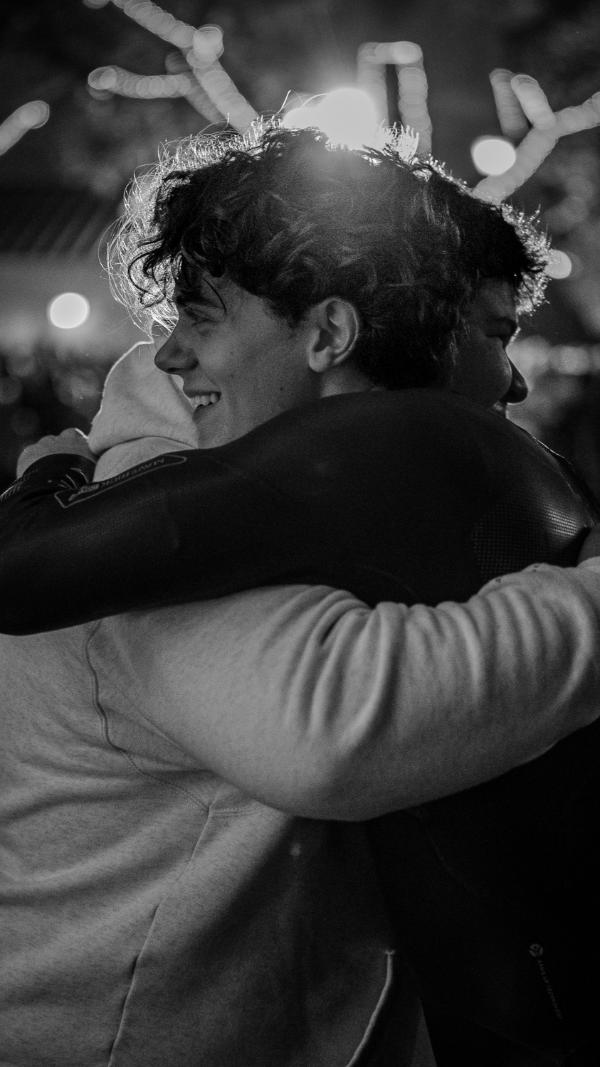 Black-and-white photo of Aidan hugging a friend after a race