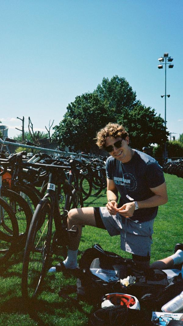 Aidan in sunglasses sitting by the bike racks
