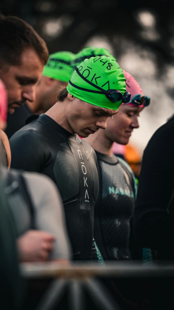 Athletes in green swim caps waiting at the swim start