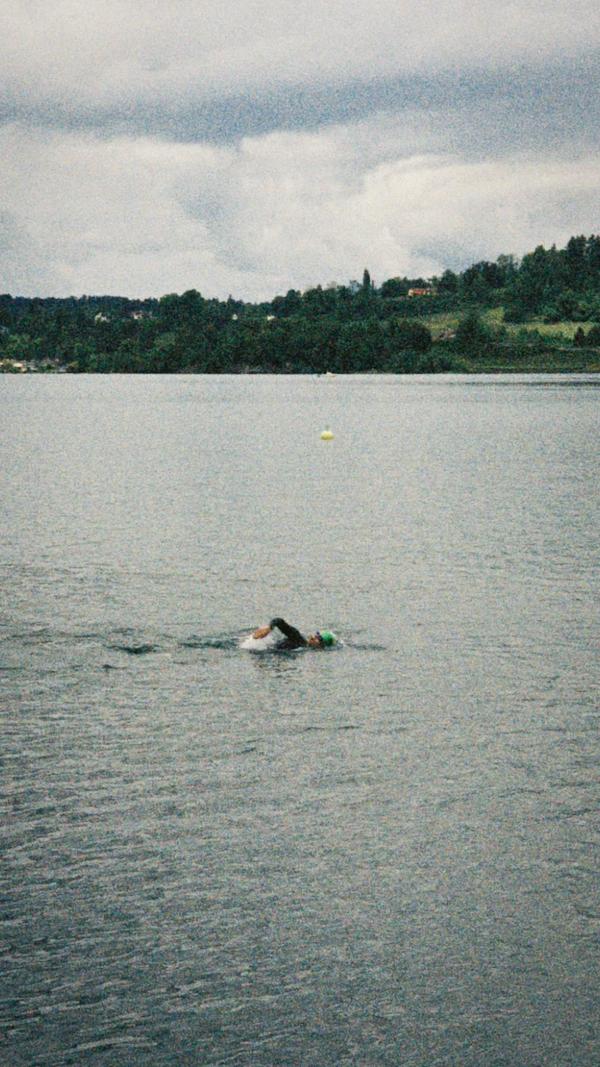 A lone swimmer on a gray lake