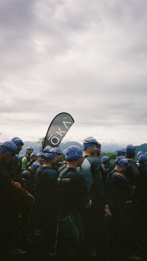 A crowd of swimmers in caps beside a ROKA flag